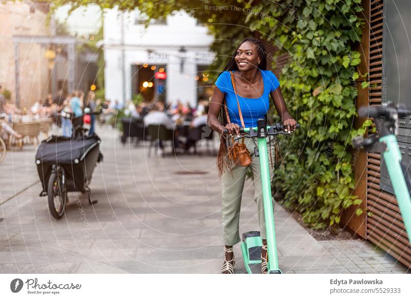 Portrait of a happy young woman riding an electric scooter in the city adult attractive beautiful black confidence confident cool female girl hairstyle leisure