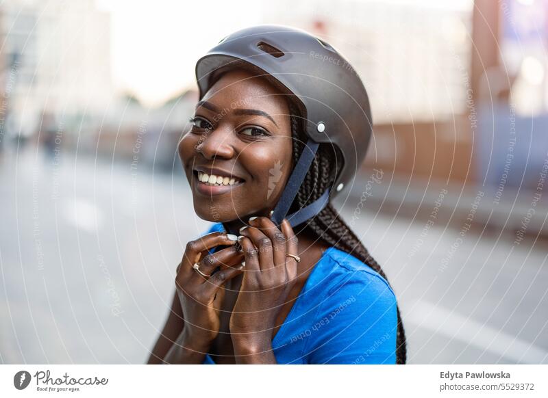 Young woman putting her cycling helmet on adult attractive beautiful black confidence confident cool female girl hairstyle leisure lifestyle natural one person