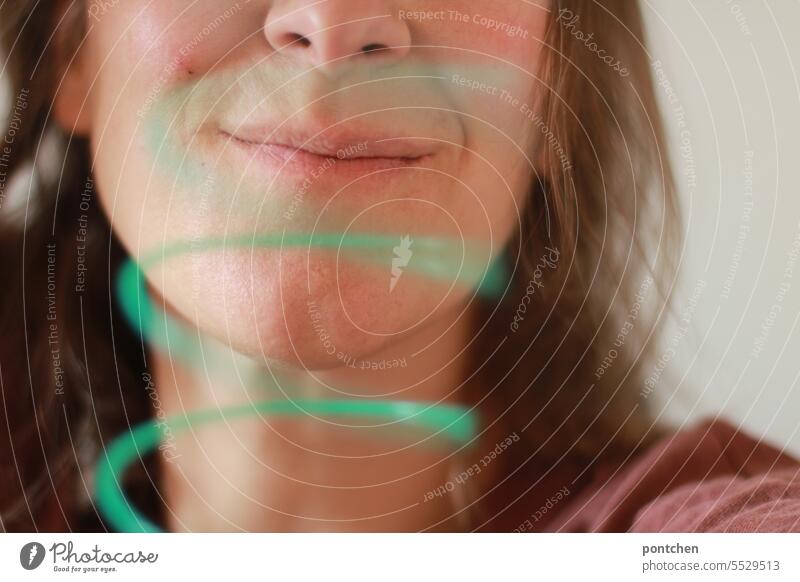 a green spiral in front of the face of a smiling woman. Face Woman Smiling Funny variegated Movement Toys Green Spiral game Joy Mouth Ease Dynamics Round