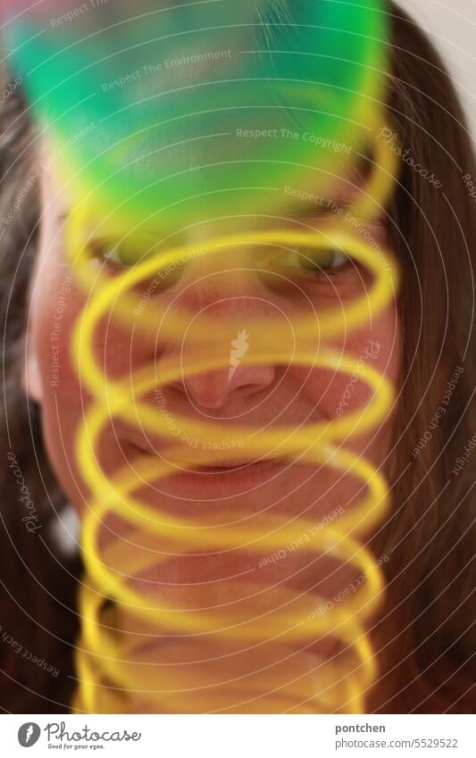 a green and yellow spiral in front of the face of a smiling woman. Face Woman Smiling Funny variegated Movement Rainbow Toys Green Yellow Spiral game havoc