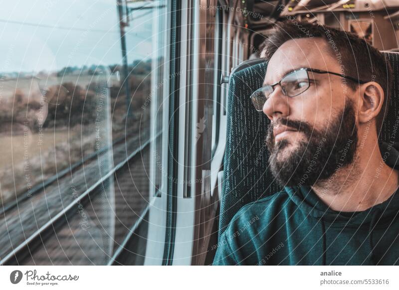 Man traveling solo by train looking outside the window male beard bearded glasses eye Eyeglasses traveler Train looking out of window Sadness sad Goodbye