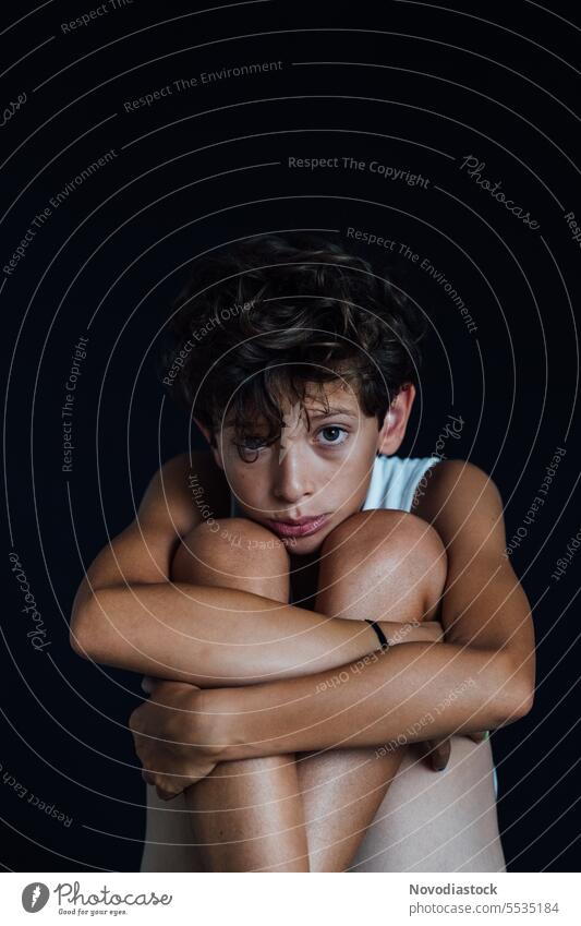 Portrait of a 10 year old boy looking sad, black background portrait young casual upset depressed mental health caucasian child male close up handsome cute