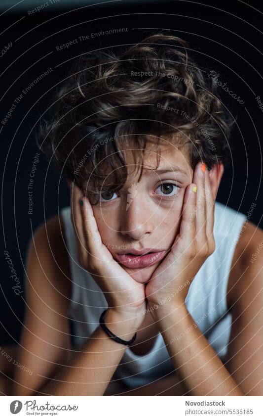Portrait of a 10 year old boy, painted nails, vertical portrait young casual sad upset depressed mental health caucasian child male close up black background