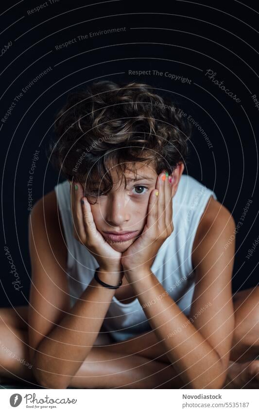 Portrait of a young boy looking sad, vertical photo portrait 10 year old casual upset depressed mental health caucasian child male close up black background