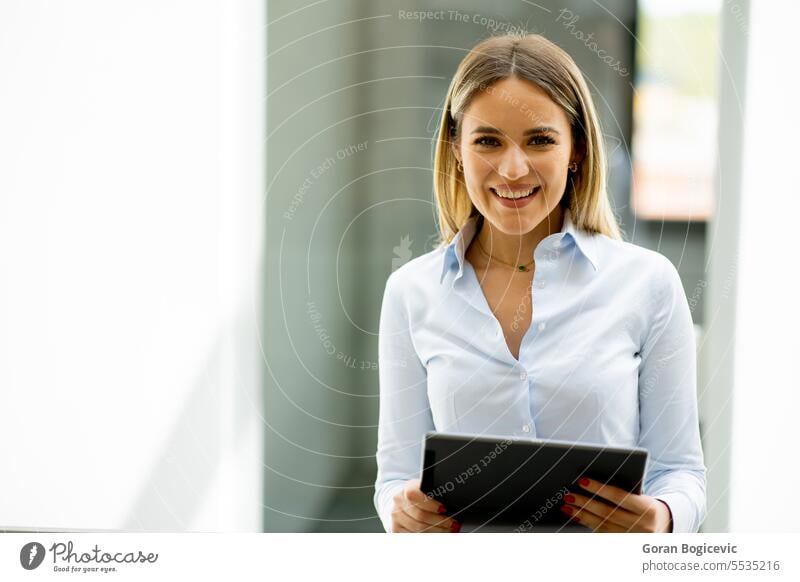 Young woman with digital tablet standing in the modern office hallway adult attractive beautiful business businesswoman casual cheerful communication company