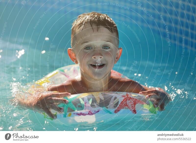 Portrait smiling boy in swimming pool, child with inflatable ring. Summer vacation or classes. Summertime and swimming activities for happy children on the pool
