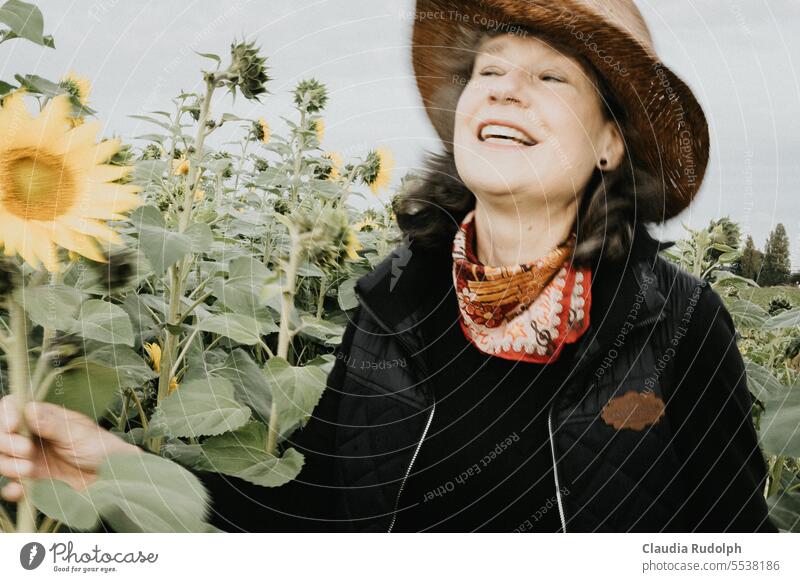 Blurred shot of laughing woman with straw hat in sunflower field Sunflower field late summer early autumn Middle aged woman gardener Laughter Happy Joy