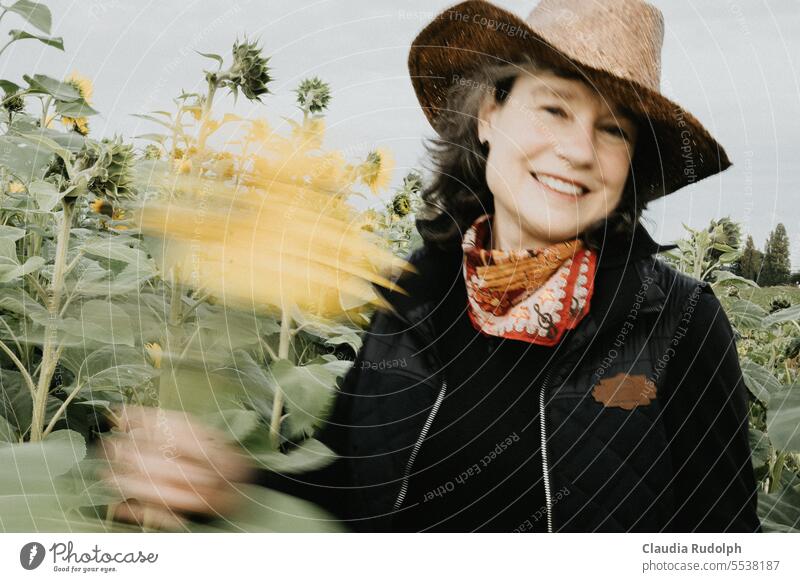 Blurred shot of smiling woman with straw hat in sunflower field waving flower Sunflower field Smiling blurred Rudbeckia Straw hat Cowboy hat Happy fortunate Joy