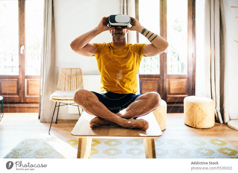 Man in VR headset exercising in light room man yoga lotus pose vr virtual reality practice meditate goggles male digital detox cyberspace mindfulness simulate