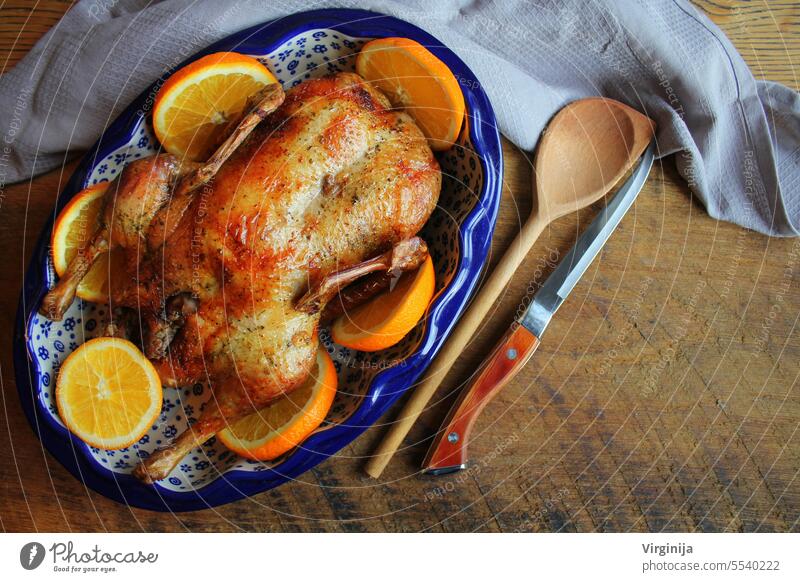 Whole crispy golden roast duck with marinated with fresh orange slices for a festive . Top view rustic wooden background. christmas family party food fruit leaf