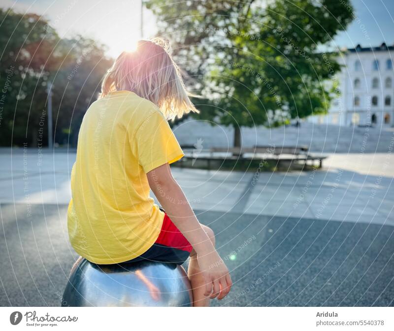 Child spinning sitting on metal ball in city with back light Boy (child) Blonde Hair and hairstyles Park Town Head Exterior shot Youth (Young adults)