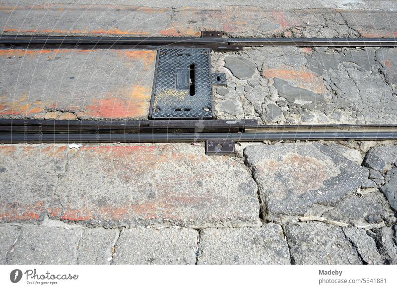 Rails and tracks of the streetcar between old gray and crumbling paving stone in a pedestrian zone in the sunshine in Bursa at the Uludag Mountains in Turkey