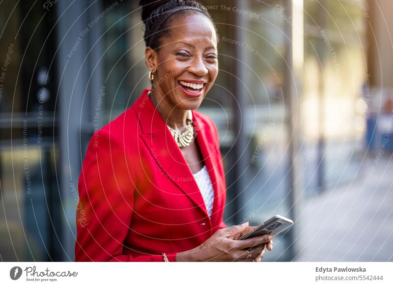 Portrait of smiling mature business woman using cell phone in urban environment people Downtown Businesswoman Joy Woman Black naturally Attractive City
