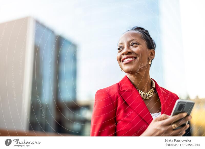 Portrait of smiling mature businesswoman using mobile phone in urban setting people downtown joy black natural attractive city black woman happiness street