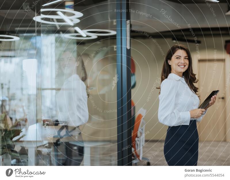 Young woman with digital tablet walking in the modern office hallway adult attractive beautiful business businesswoman casual cheerful communication company