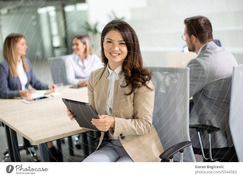 Young woman with digital tablet in the modern office in front of her team adult attractive beautiful business businesswoman casual cheerful communication