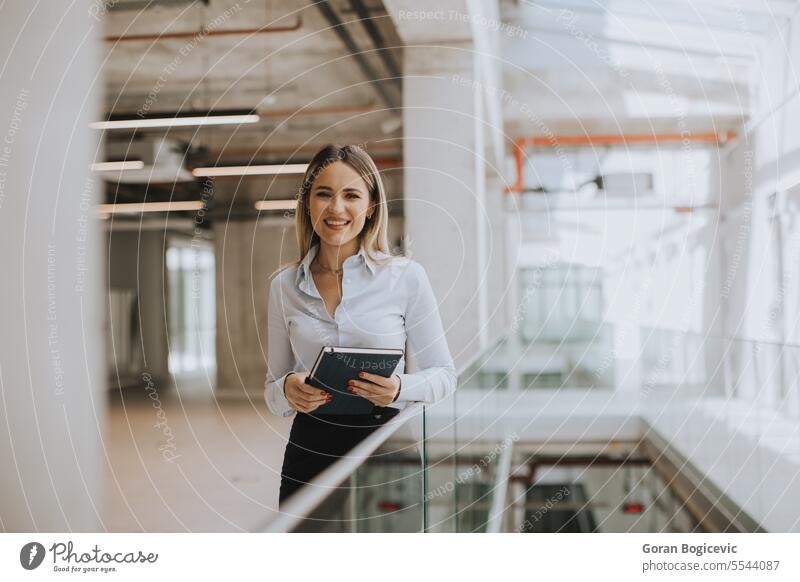Young woman with notebook standing in the modern office hallway adult attractive beautiful business businesswoman casual company confident corporate paper