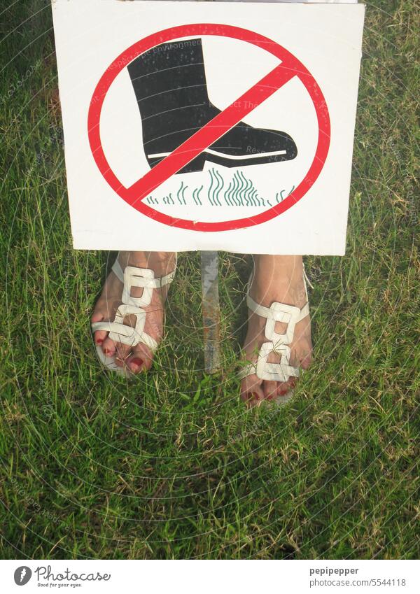 No trespassing - young woman stands with both feet on a lawn, despite a prohibition sign Signs and labeling Bans Signage Prohibition sign Warning sign