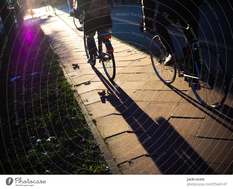cycling in the city Bikers cyclists Sidewalk Bicycle Lifestyle Shadow Silhouette urban Cycling Movement Berlin Paving tiles Warmth Shadow play Sunlight