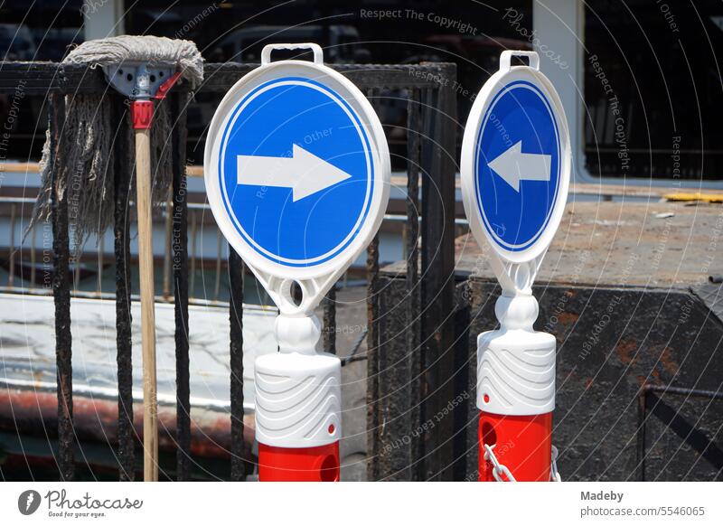 Stand in red and white with blue round traffic signs with white direction arrow at the pier of the ferry in Eminönü at the Galata Bridge in Istanbul on the Bosphorus him Turkey
