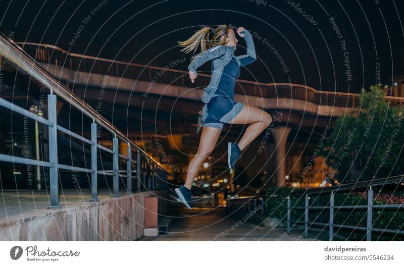 Woman jumping in cardio training exercise on the city at night woman sport female doing young flying empty urban copy space right action motion blonde posture