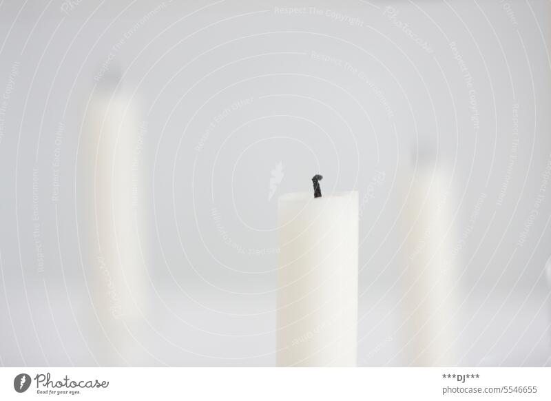 Three white staggered candles whose flame is no longer burning shoulder stand Wick Wax Burn symbol from Grief Light blurriness tone-in-tone beeswax paraffin wax