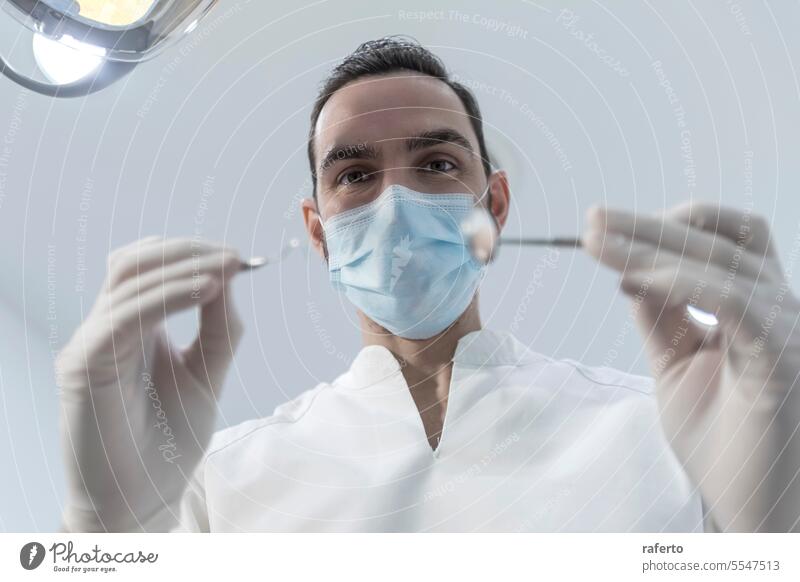 Low angle shot of a male dentist, doing the exam and checking up on oral health of the patient teeth cavity clinic clinical dental dentistry doctor examine