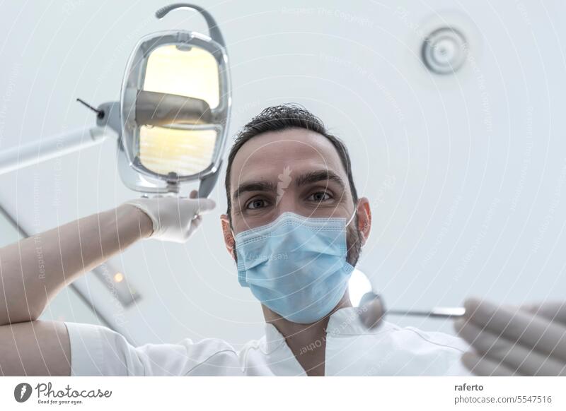 Low angle shot of a male dentist, doing the exam and checking up on oral health of the patient teeth cavity clinic clinical dental dentistry doctor examine