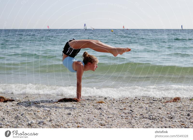 Gymnast on beach in gymnastics pose Beach turnrn Yoga contorsion Sports Movement Fitness Healthy Sports Training Waves Ocean Surfer Surfing Sail Water youthful