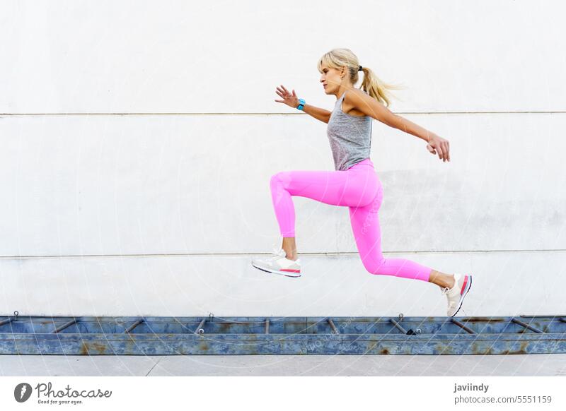 Woman in sportswear running on street in daylight woman runner workout jog exercise training fitness cardio female brown hair bare shoulders leggings endurance