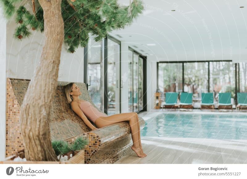 Young woman relaxing by the indoor swimming pool beauty wellbeing indoors poolside resting relaxation people water looking young adult freshness one person