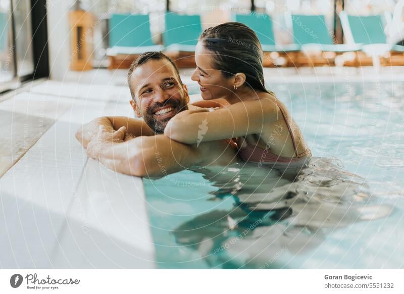 Young couple relaxing in the indoor swimming pool adult attractive beautiful beauty bikini body caucasian day enjoy enjoying female happy hold lifestyle love