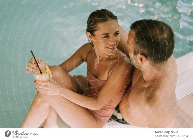 Young couple relaxing by the indoor swimming pool woman happy wellness female water adult love young caucasian enjoy poolside luxury beauty beautiful bikini