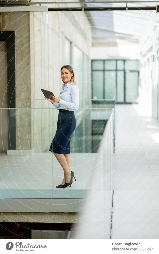 Young woman with digital tablet walking in the modern office hallway adult attractive beautiful business businesswoman casual cheerful communication company