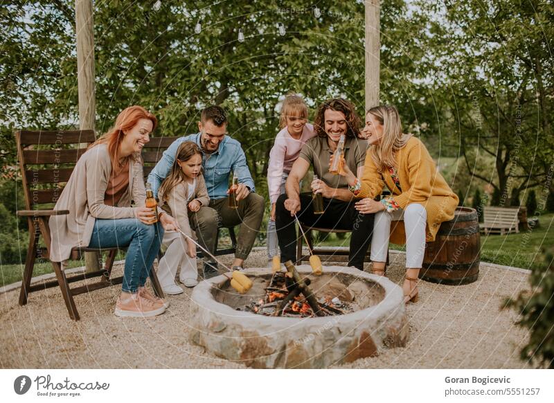 Friends having good time and baking corns in the house backyard father woman parent family adult barbecue bbq casual caucasian charcoal grill cheerful closeup
