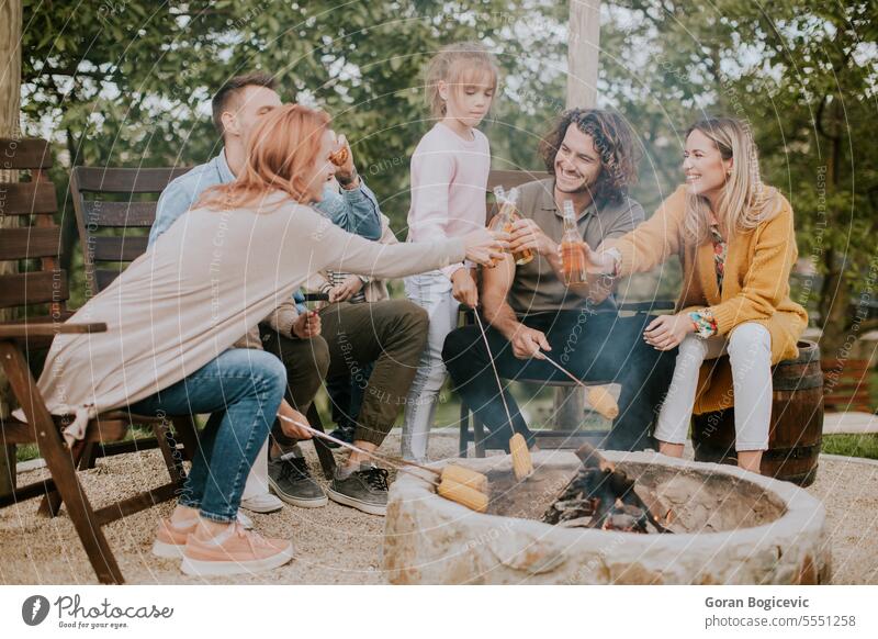 Friends having good time and baking corns in the house backyard father woman parent family adult barbecue bbq casual caucasian charcoal grill cheerful cider