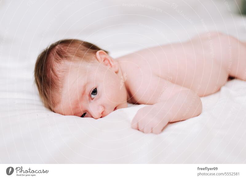 portrait of a newborn in studio lighting against white baby firstborn laying laying down copy space parenthood motherhood innocence life labor young boy happy