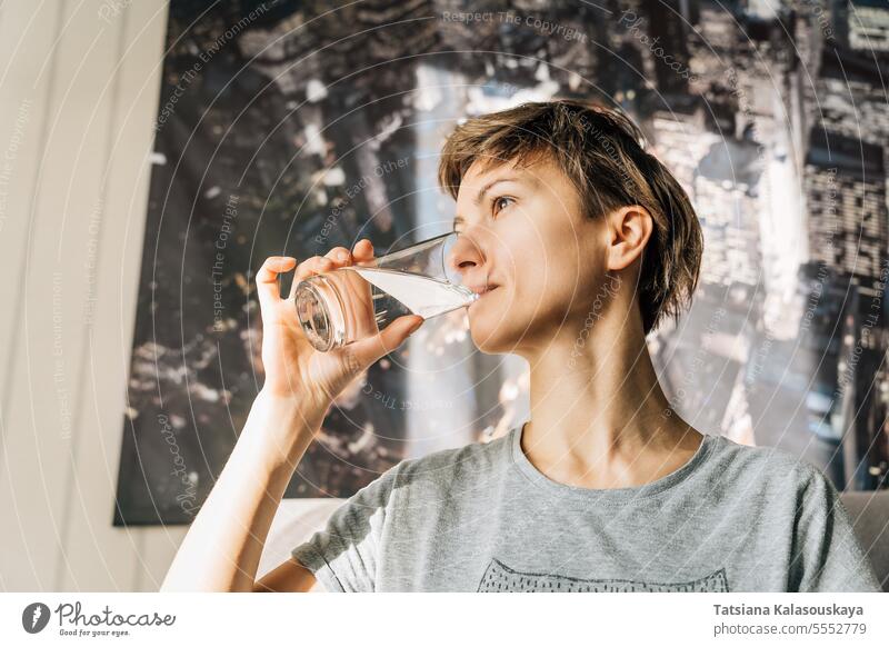 A young woman with short hair drinks water from a glass female people Lifestyle Drink person Drinking caucasian Glass 30-40 years Dishes Water Glass Calm