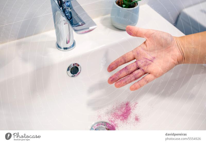 Close up of unrecognizable woman removing purple glitter of her hand into washbasin at bathroom cleaning micro plastic microplastics polluting pollution water