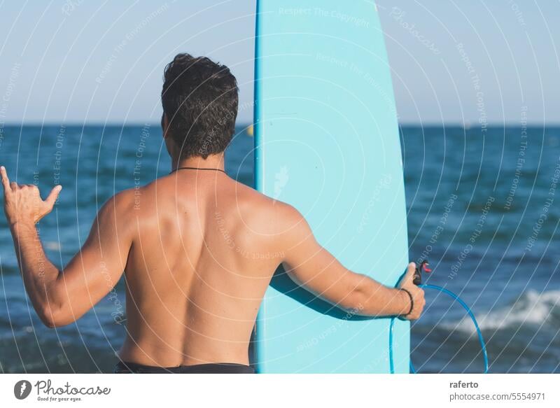 A man standing on the shore holding a surfboard - view from the back male person sport surfer lifestyle beach sea surfing sand ocean leisure water coast outdoor