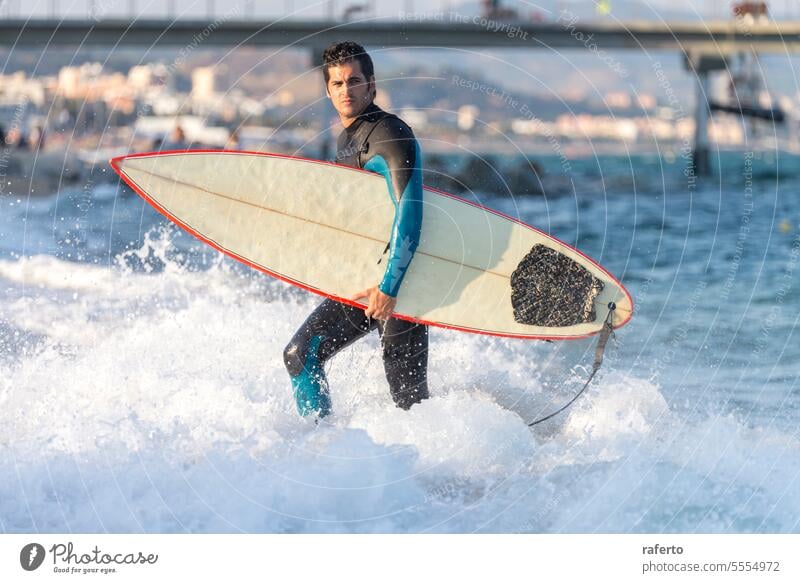 Young man surfer holding surfboard coming out from the waves imagebrief teenage guy hobby profile recreation shore youth boy carry happiness male people sport