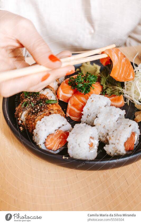 close up of a sushi plate with female hands chopsticks lifestyle closeup healthy fish japanese delicious dish appetizer tasty maki recipe asia cuisine lunch