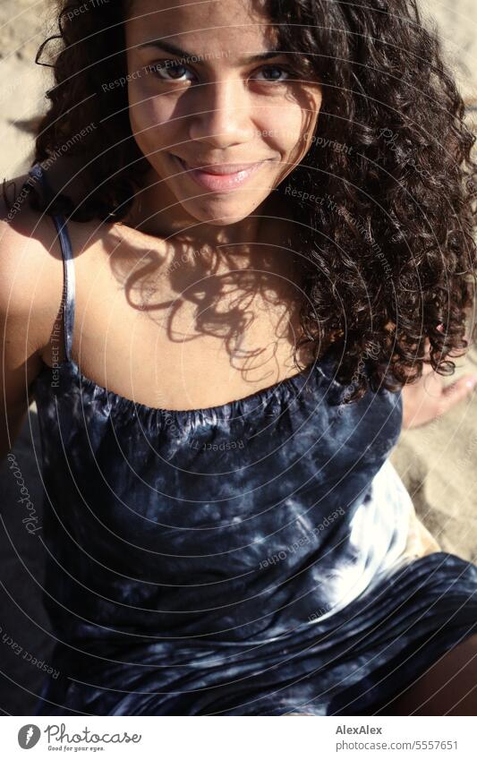 a young beautiful woman sits on the beach in summer and looks into the camera Woman Young woman Curly pretty Slim attractive good-looking emotion Model Esthetic