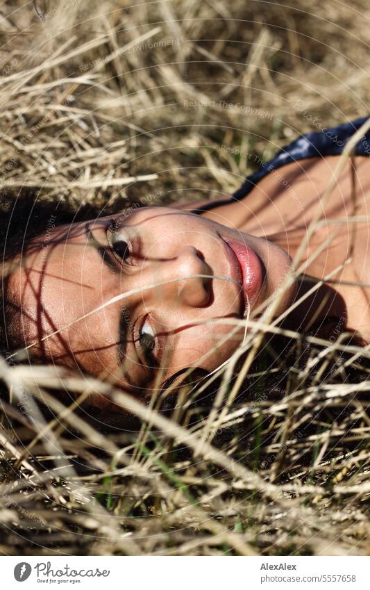 young beautiful woman lying in tall grass looking at camera Woman Young woman Curly pretty Slim attractive good-looking emotion Model Esthetic Adults