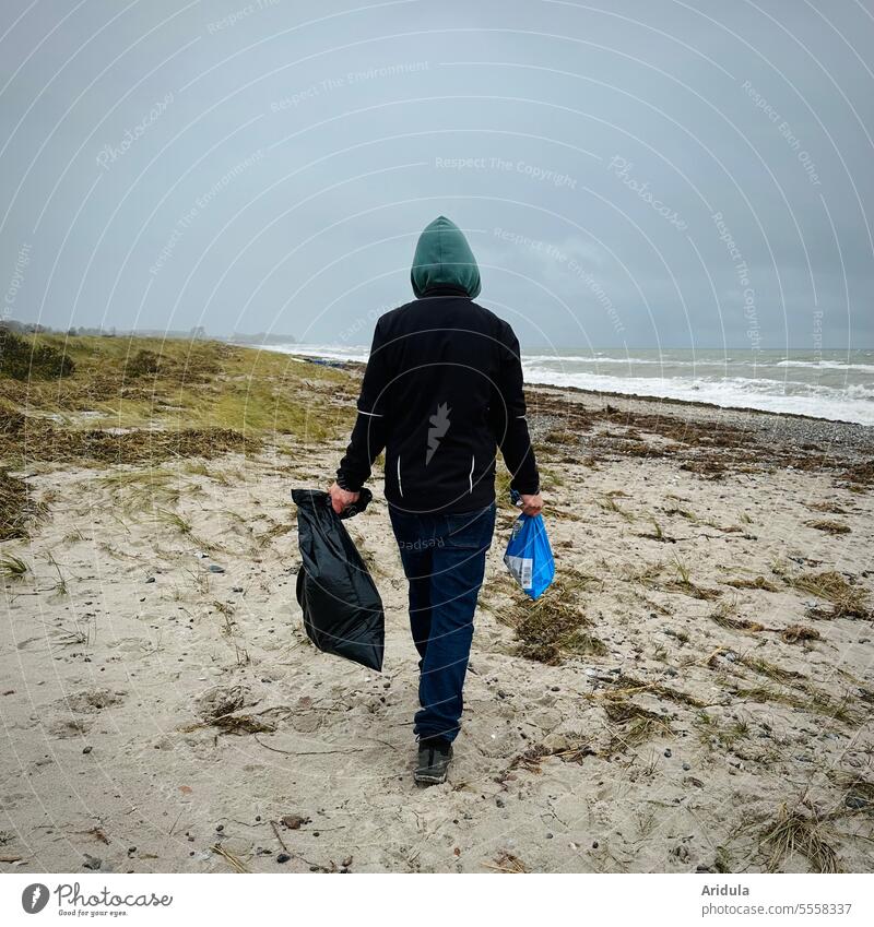 Man walking along beach with two bags in hand to collect garbage Beach Garbage bags Trash amass Environment Environmental pollution coast Ocean Plastic Nature