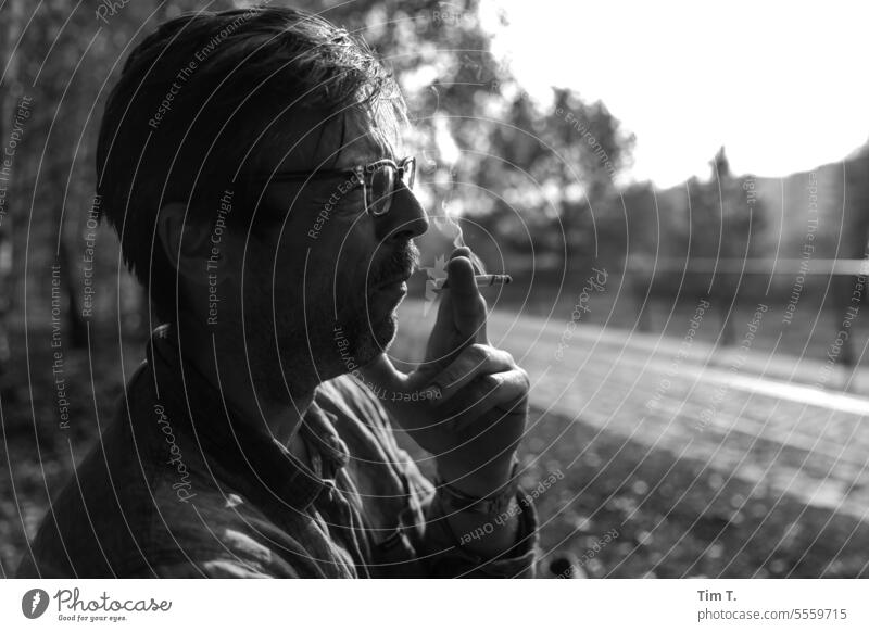 Man with glasses smokes Eyeglasses Smoking b/w Black & white photo Day B/W Exterior shot B&W Berlin Calm bnw Cigarette Loneliness