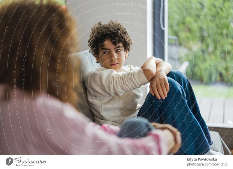 Upset boy sitting on sofa while his mother looking at him real people adult apartment bonding child family female home indoors kid lifestyle love mom