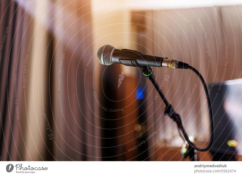 Microphone on stand on stage close up with searchlight light. Professional mic at concert hall or conference room, karaoke, night club, bar. Public events, festival, wedding. Copy space.