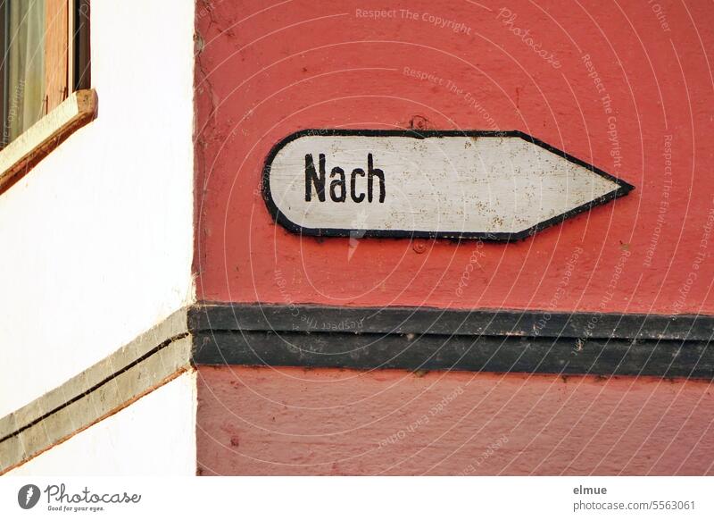 old sign with the inscription " Nach " on a red plastered house / signpost Road marking Signage Direction house wall groundbreaking Orientation