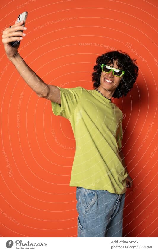 Happy young ethnic man taking selfie with smartphone sunglasses smile using happy positive cheerful male stand latin american hispanic mobile style gadget
